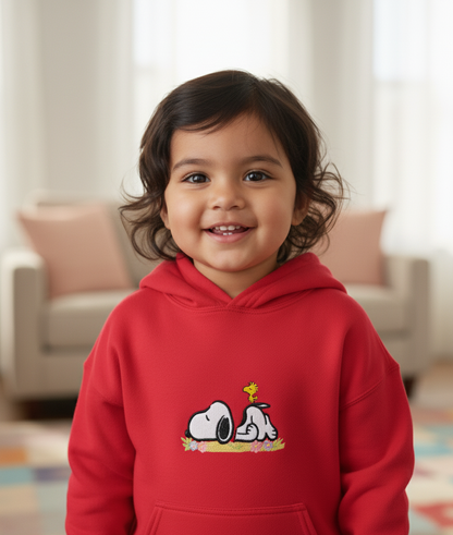 Child wearing a red hoodie with a cartoon Snoopy character design, embroidered.