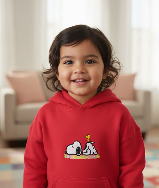 Child wearing a red hoodie with a cartoon Snoopy character design, embroidered.