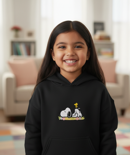 Young girl wearing a black hoodie with a Snoopy cartoon design, embroidered.