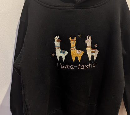 Black hoodie with embroidered llamas in beautiful threads and 'Llama-tastic!' text on a plain background