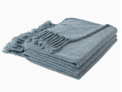 Folded blue blanket with tassels on a white background