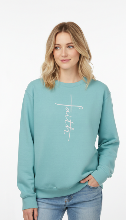 Woman wearing a teal sweatshirt with 'faith' in a cross shape embroidered on it in white thread