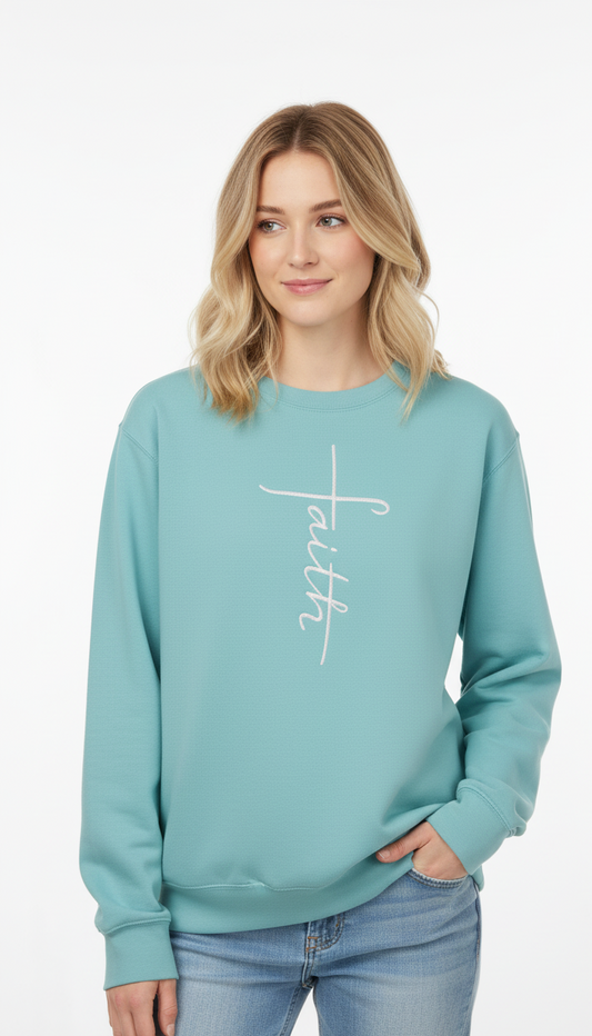 Woman wearing a teal sweatshirt with 'faith' in a cross shape embroidered on it in white thread