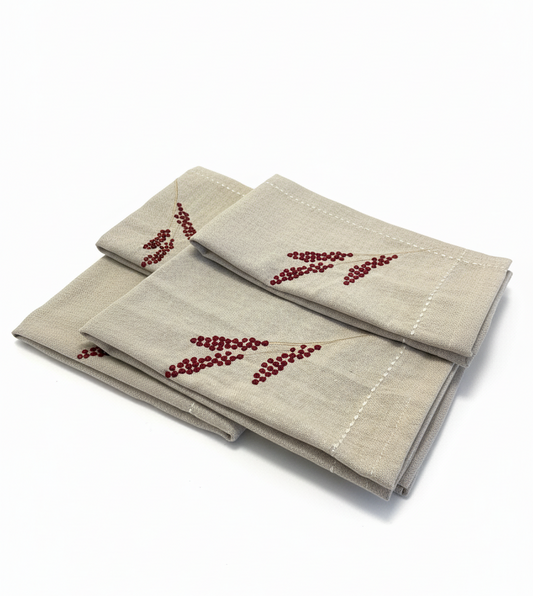 Set of three beige napkins with red bead patterns on a white background
