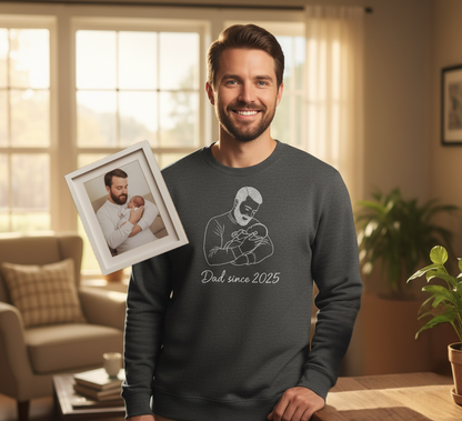 Man wearing a sweater with 'Dad since 2025' and an outline of him holding his baby embroidered on the sweatshirt.